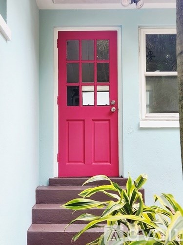 A red door is on the left side of a white window.