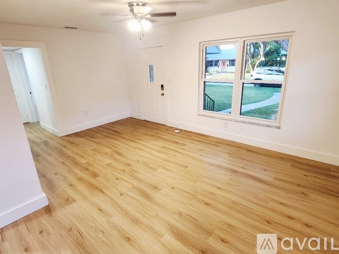 A room with wooden flooring and a window showing a street view.