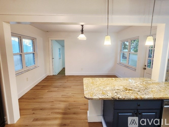 A kitchen with a granite countertop and wooden floors.