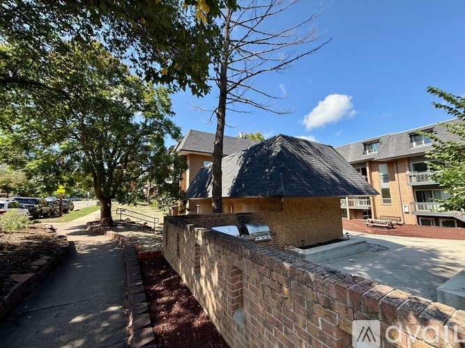 A sunny day in a residential area with a brick wall and a tree.