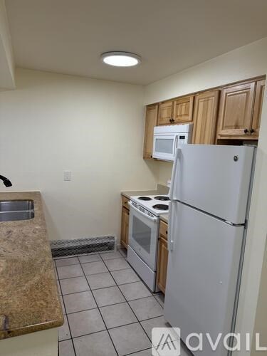 A kitchen with a white refrigerator, a microwave above the stove, and wooden cabinets.
