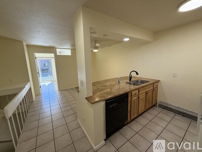 A kitchen with a black dishwasher and wooden cabinets.