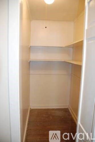 A small, empty room with a wooden floor and white walls.