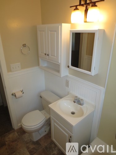 A bathroom with a toilet, sink and cabinet.