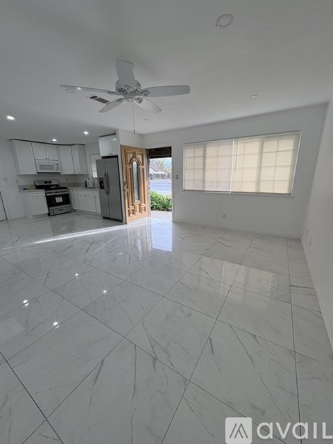 A spacious kitchen with a ceiling fan and a view of the backyard.
