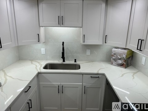 A kitchen with white cabinets and a marble countertop.