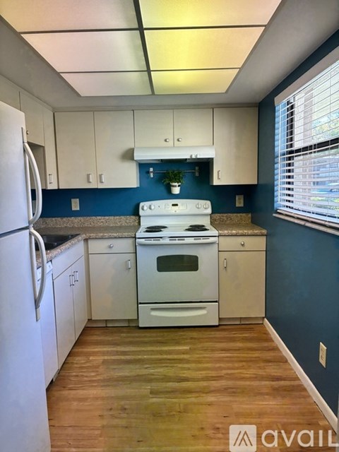 A kitchen with white appliances and wooden floors.