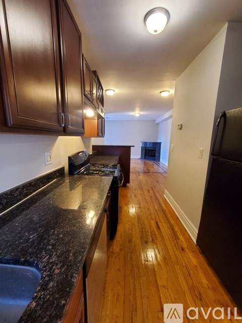 A kitchen with dark wood cabinets and a black granite countertop.