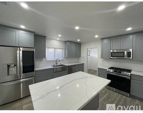 A modern kitchen with stainless steel appliances and a marble island.