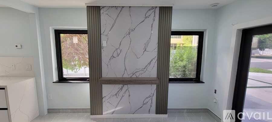 A bathroom with a marble slab wall and a window.