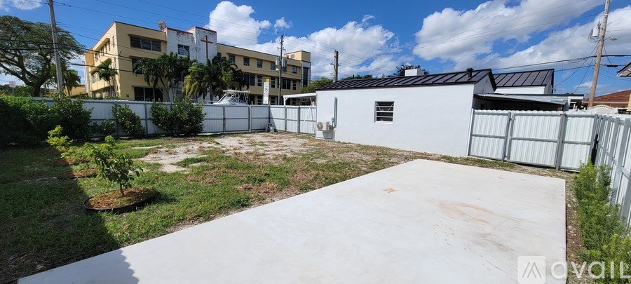 A white house with a grey fence in front of a yellow building.