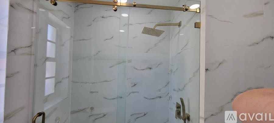 A bathroom with a marble wall and a glass shower stall.