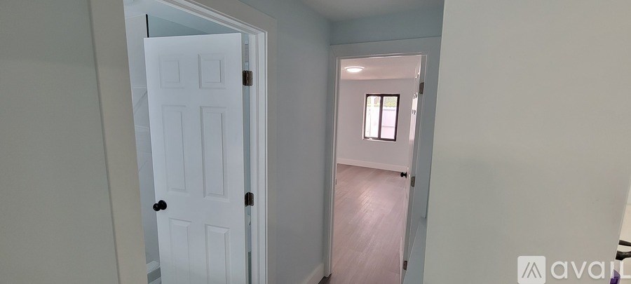 A white door is open to a room with a window.