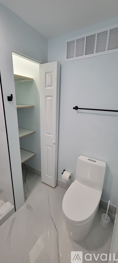A white toilet in a bathroom with a white door and a white toilet paper roll.