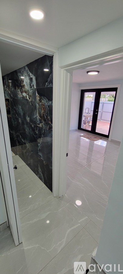 A hallway with marble flooring and a glass door.