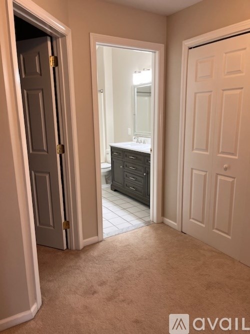 A bathroom with a vanity and mirror is visible through an open door.
