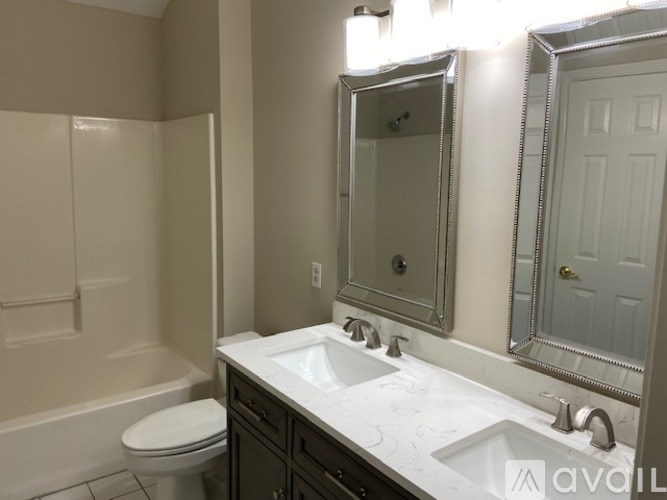 A bathroom with a toilet, sink, and mirror.