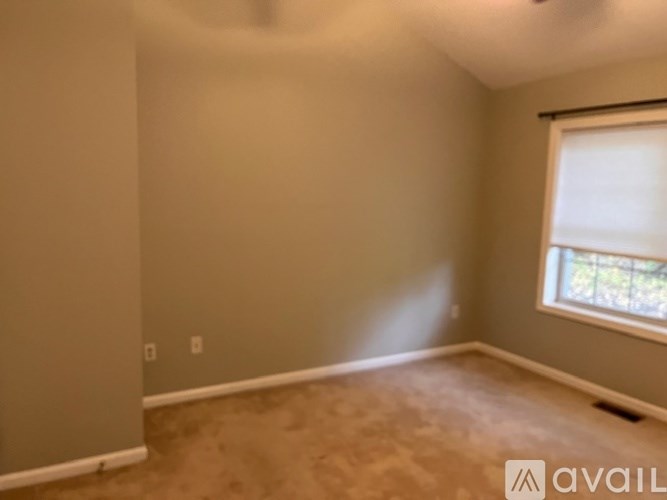 A room with a window and a carpeted floor.
