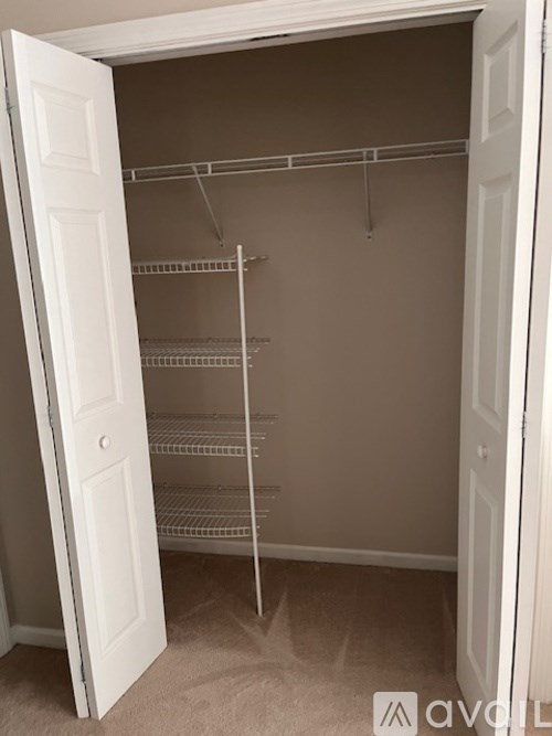 Empty white closet with shelves and hangers.