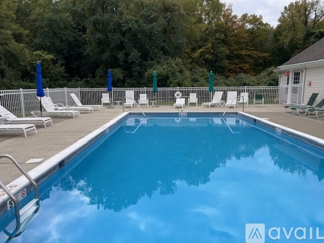 A pool surrounded by a white fence and trees.