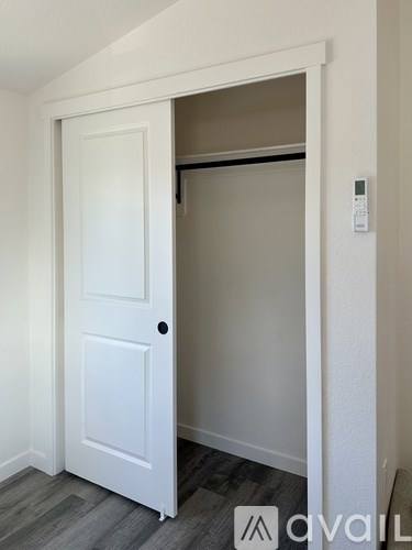 A white door is open to a room with a grey floor.