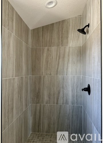 A shower area with a tiled wall and a shower head.