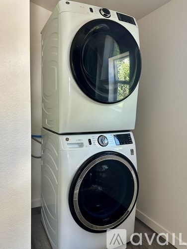 A white front load washing machine with a black door is stacked on top of another white front load washing machine with a black door.