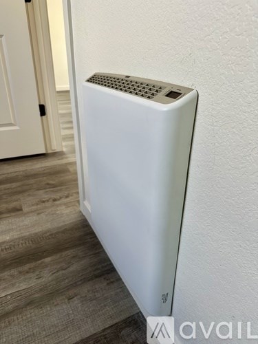 A white electric heater is mounted on a wall.