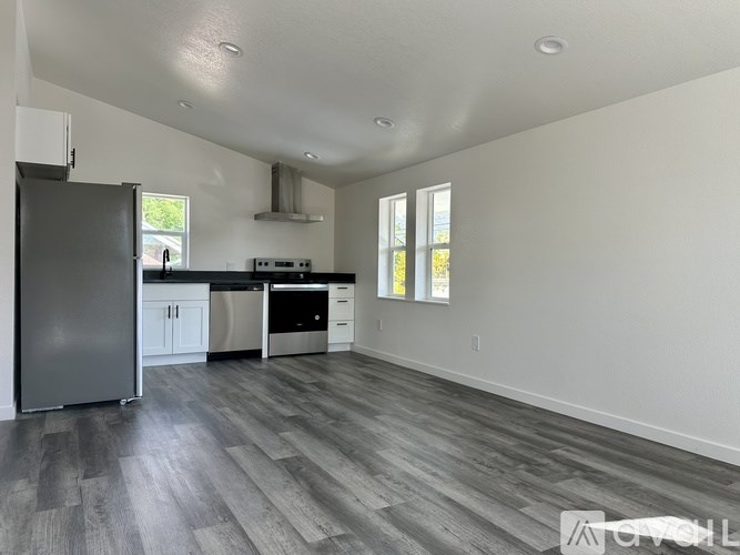 A kitchen with a black fridge and wooden floors.
