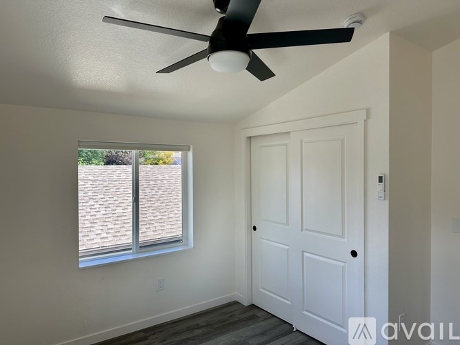 A room with a ceiling fan and a window with blinds.