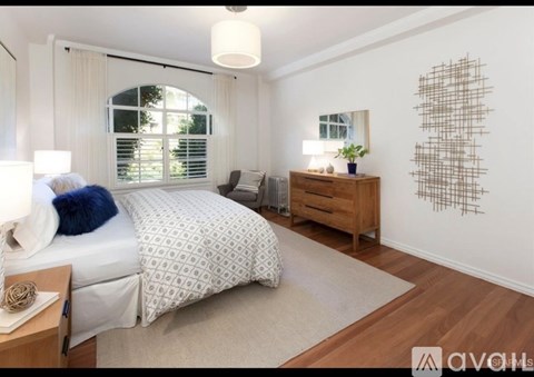 A bedroom with a large bed, a nightstand, and a wall art piece.