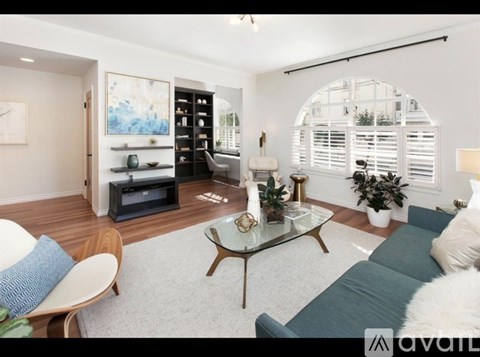 A modern living room with a glass coffee table and a grey sofa.