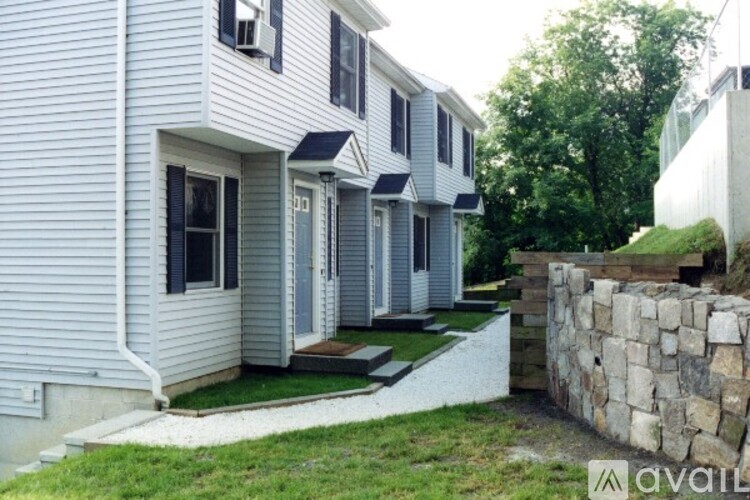 A white house with a stone wall in front.