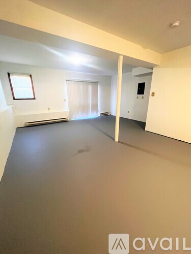 A spacious room with a window and a door leading to another room.