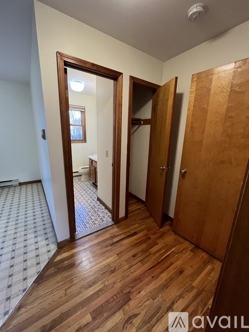 A hallway with a wooden floor and a checkered tile floor.
