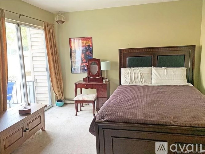 A bedroom with a bed, nightstand, chair, and window.