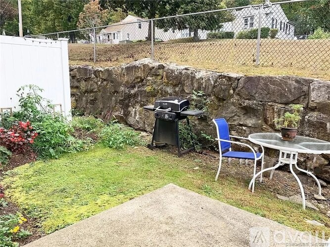 A patio with a table and chairs is surrounded by a stone wall.