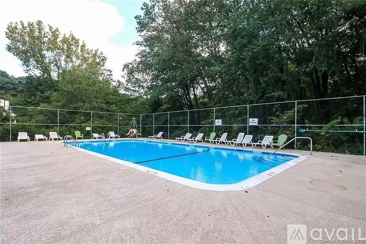 A pool surrounded by trees and chairs.