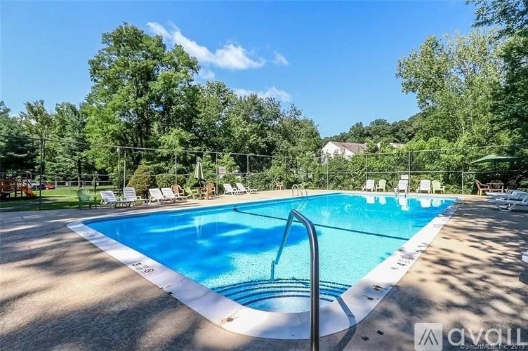 A large outdoor swimming pool surrounded by trees and lounge chairs.