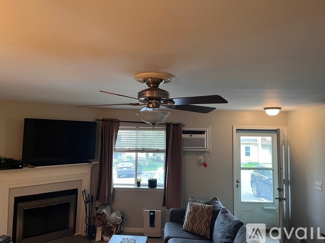 A living room with a fireplace and a ceiling fan.