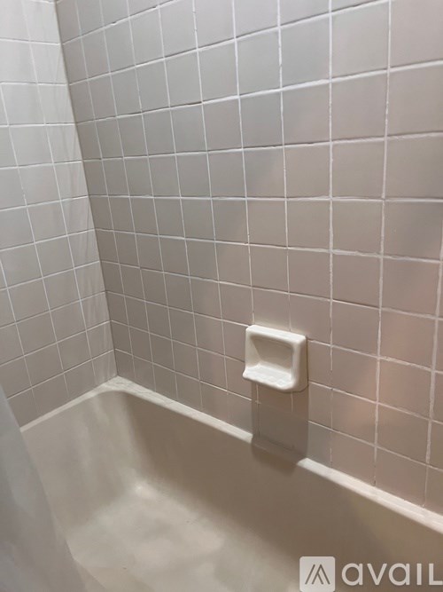 A white tiled shower with a white handle on the side.