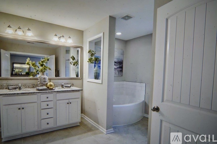 A bathroom with a white tub and a large mirror.