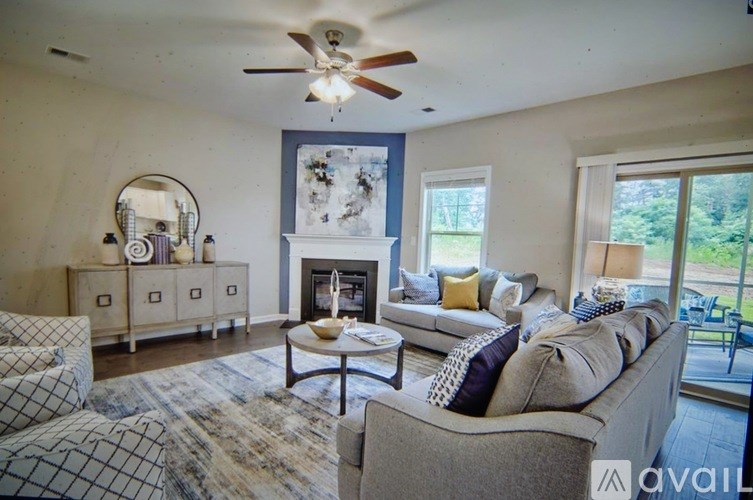 A living room with a grey couch and a fireplace.