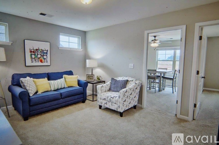 A living room with a blue couch and a white chair with a floral pattern.