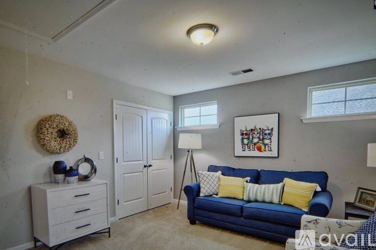 A living room with a blue couch, a white dresser, and a white cabinet.