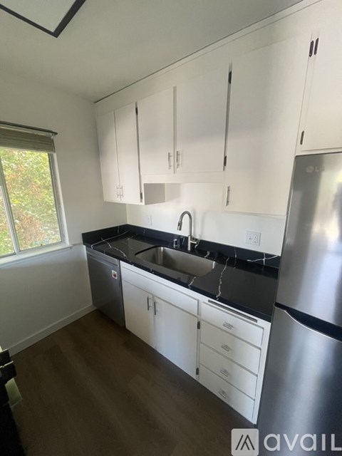 A kitchen with white cabinets and a stainless steel refrigerator.