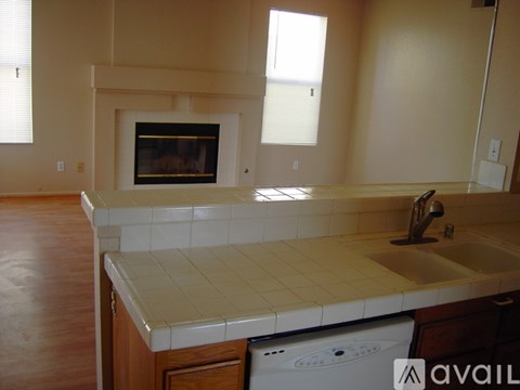 A kitchen with a white tile countertop and a white dishwasher.