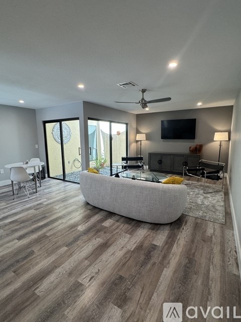 A living room with a grey sofa and a television on the wall.