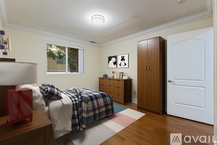 A bedroom with a bed, nightstand, and a window with a view of a balcony.