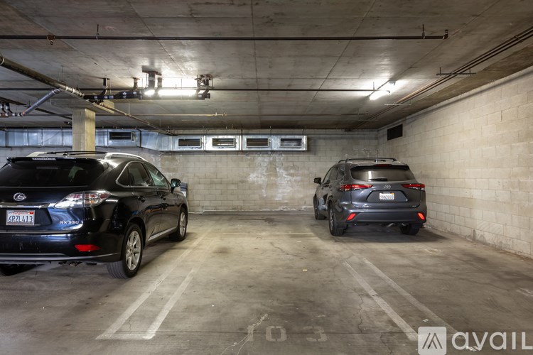 Two black cars are parked in a concrete garage.